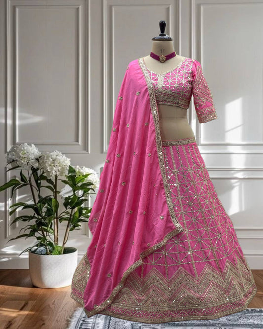 Pink embroidered lehenga on a mannequin against a white paneled wall.