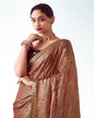 Woman wearing a brown saree with gold details on a white background