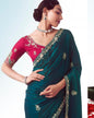 Woman wearing a teal saree with pink blouse, standing against a light blue background.