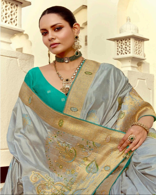 Woman wearing a traditional saree with intricate designs in an elegant setting.