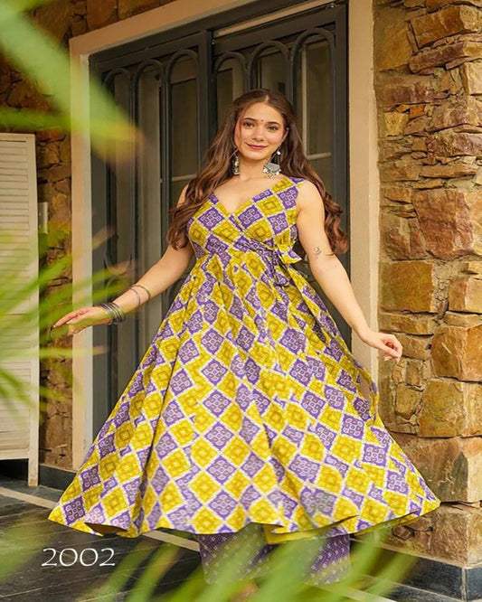 Woman in a yellow and purple checkered dress standing in front of a stone wall.