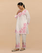 Woman wearing a light-colored kurta with pink floral embroidery on a beige background