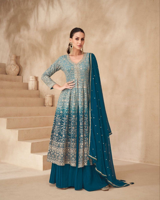 Woman in a teal traditional outfit with a matching dupatta standing on a staircase.