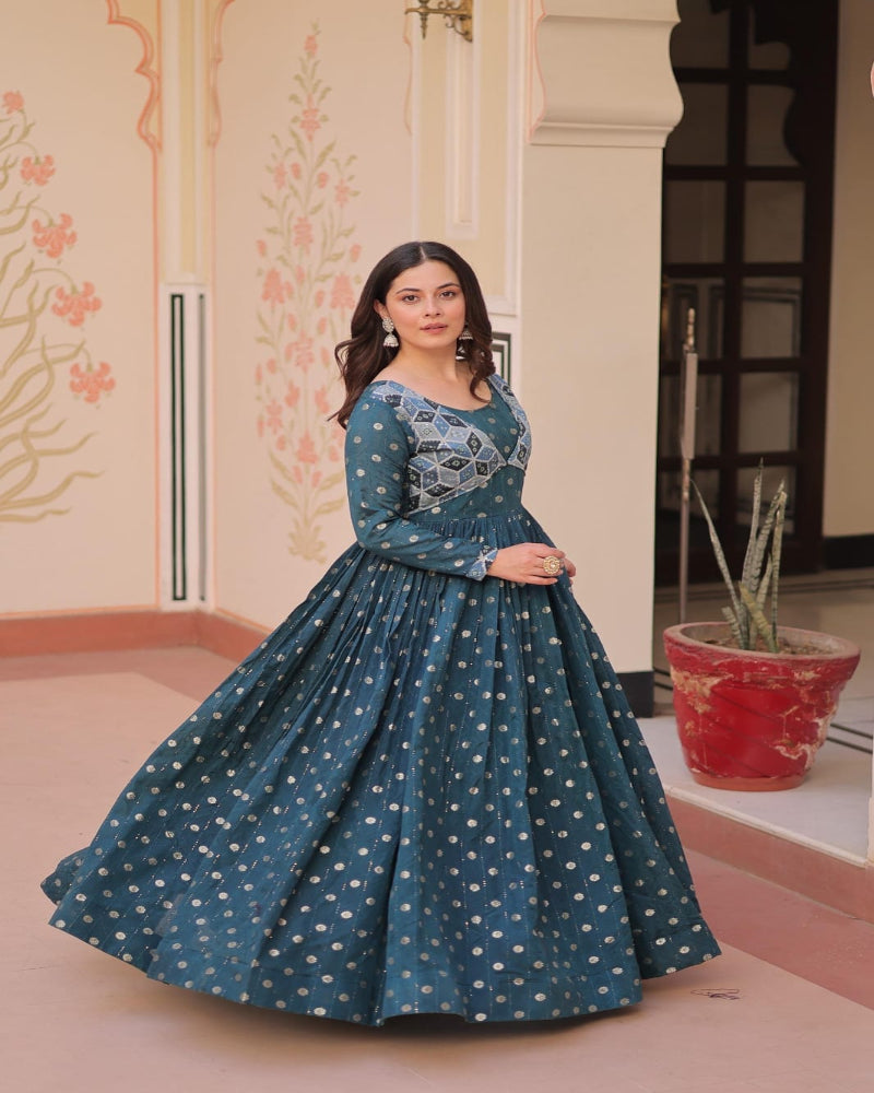 Woman wearing a teal dress with floral patterns indoors.