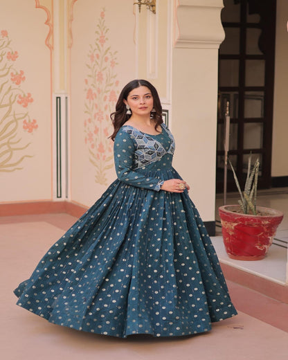 Woman wearing a teal dress with floral patterns indoors.