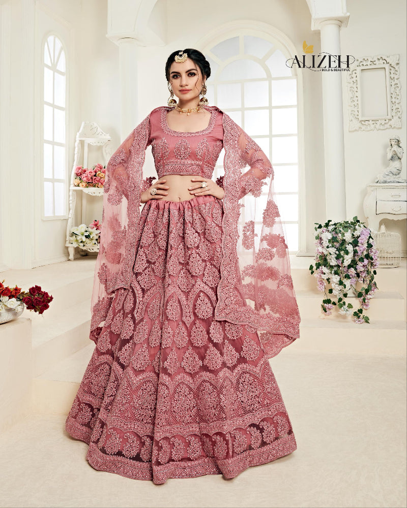 Pink traditional outfit with intricate patterns worn by a model in a well-lit room.
