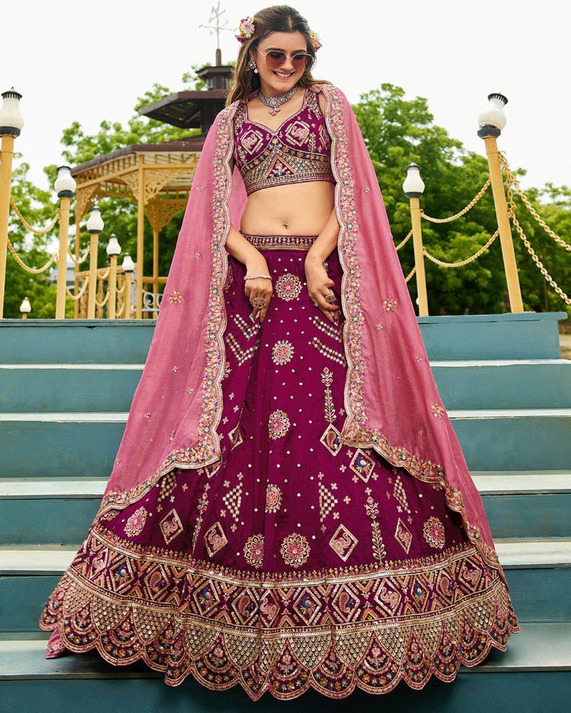 Woman in a traditional purple and pink embroidered outfit standing on steps outdoors.