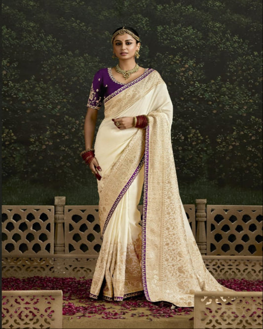 Woman in traditional Indian attire with a purple blouse and white saree, standing outdoors.