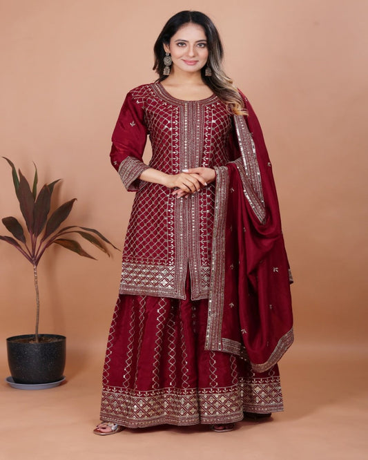 Woman wearing a maroon traditional outfit with a matching dupatta on a beige background