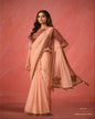 Woman wearing a peach saree with gold embroidery on a pink background